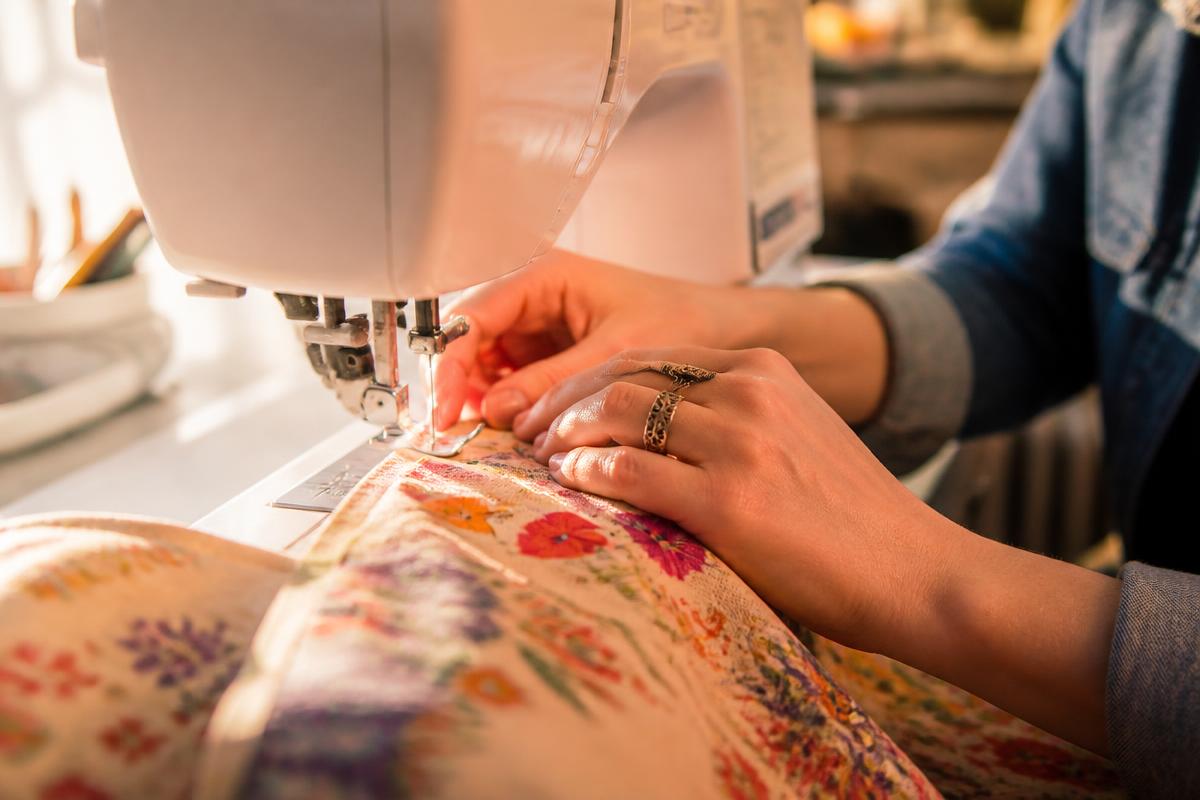 Manos guiando una tela en la máquina de coser